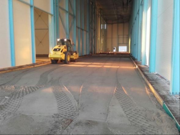 Yellow compactor working inside industrial building